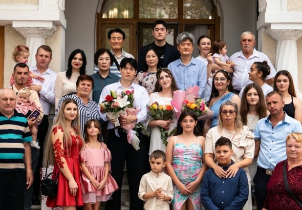 A large family posing for a group portrait on stone steps outside a building