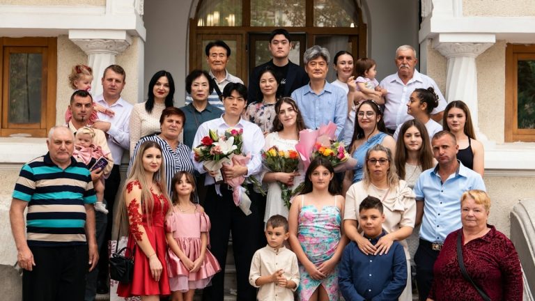 A large family posing for a group portrait on stone steps outside a building